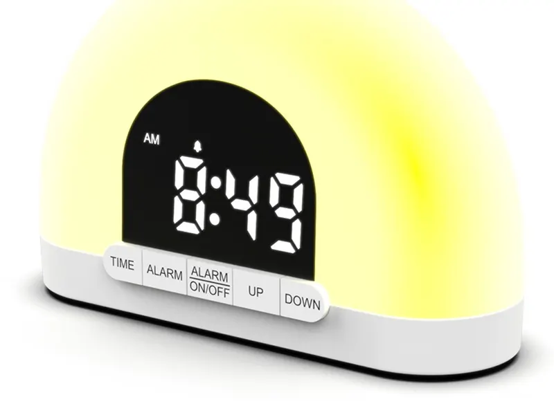 A white sunrise alarm clock with a lit dome and a digital time display